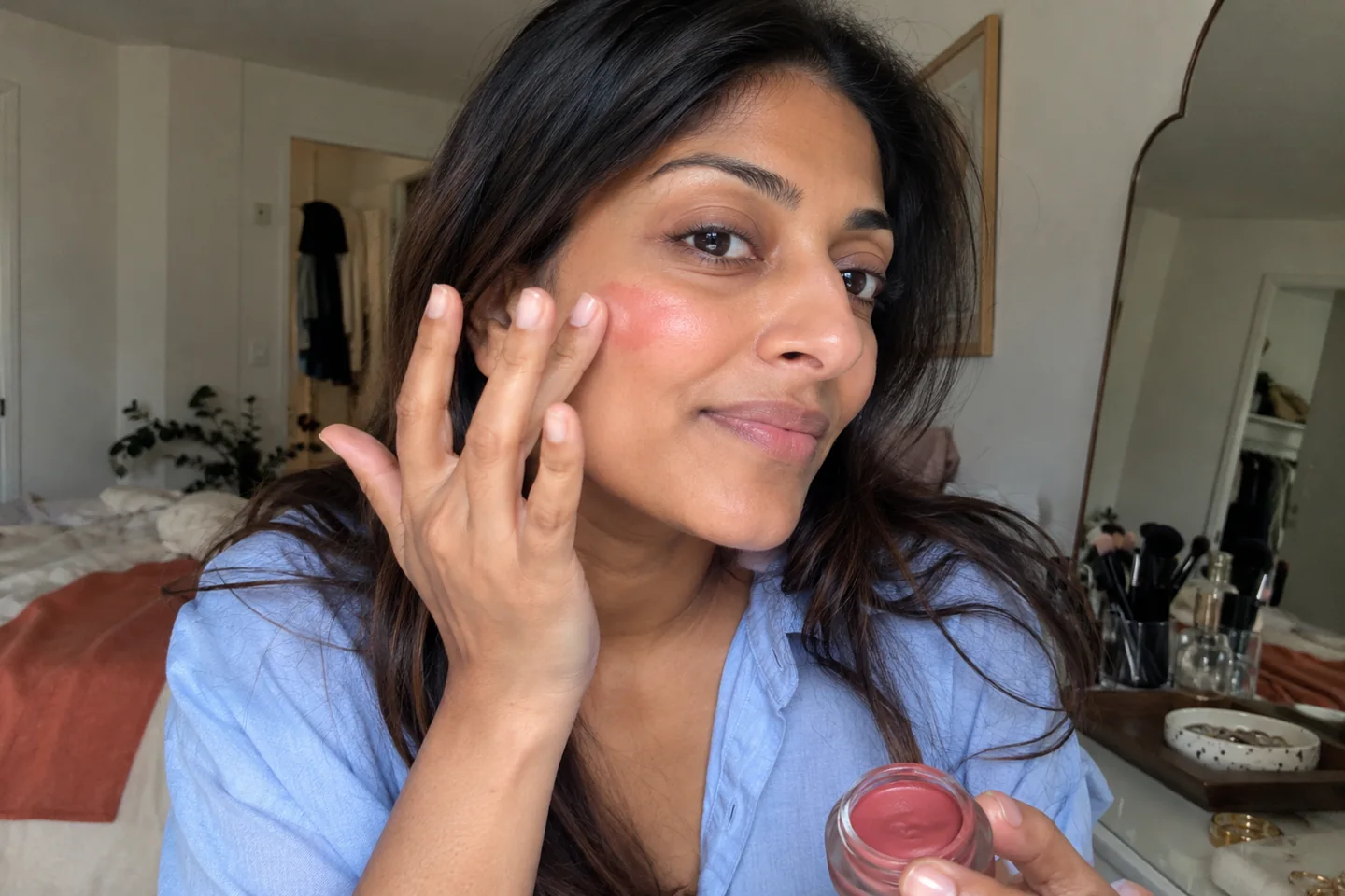 Une femme applique une petite touche de blush crème
