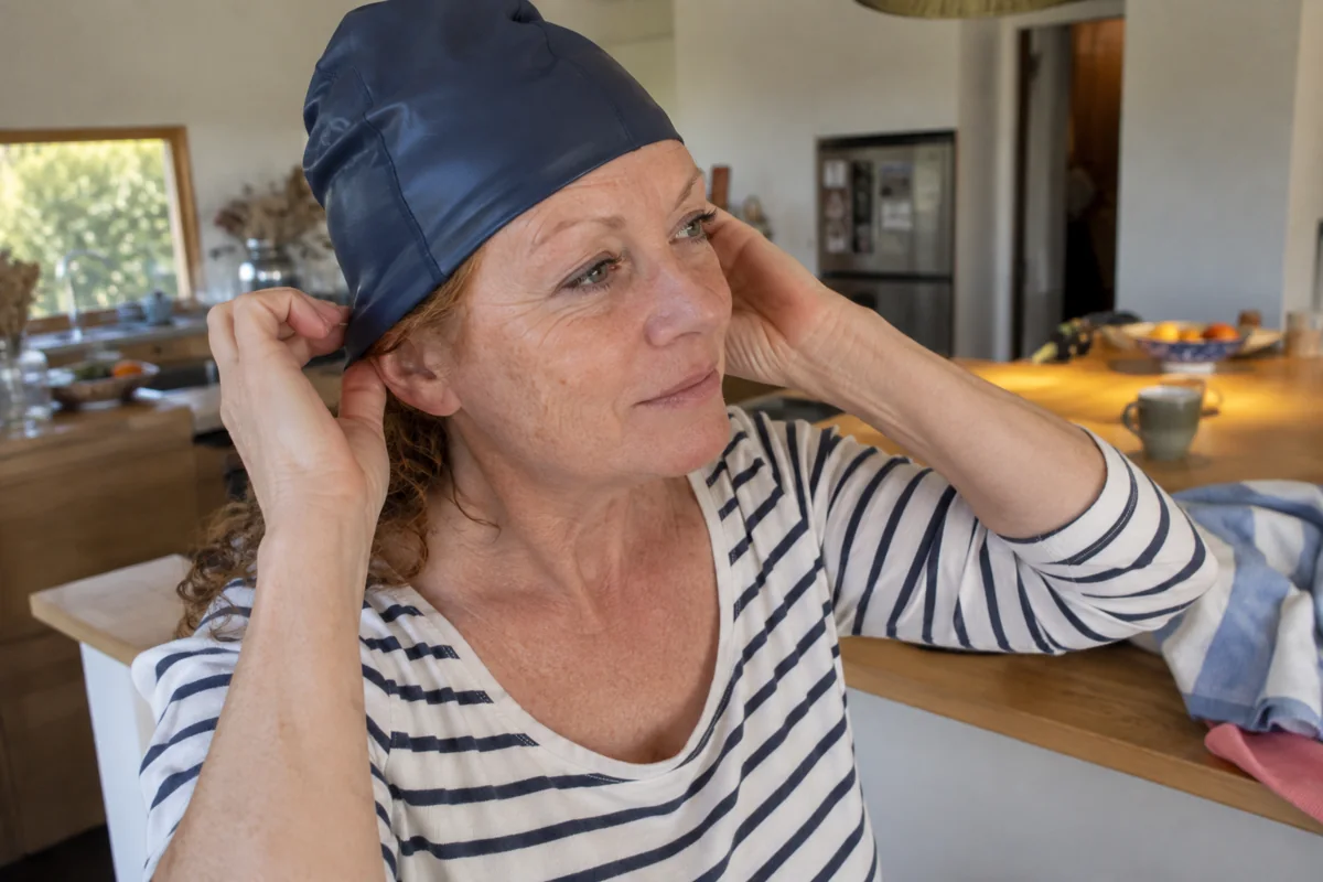 Une femme ajuste son bonnet sans tirer sur les tempes
