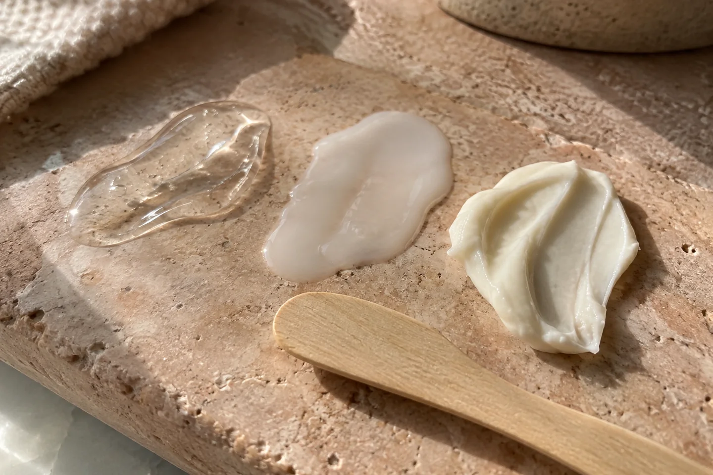 Textures de gel et de crème hydratante déposées sur une palette en pierre claire