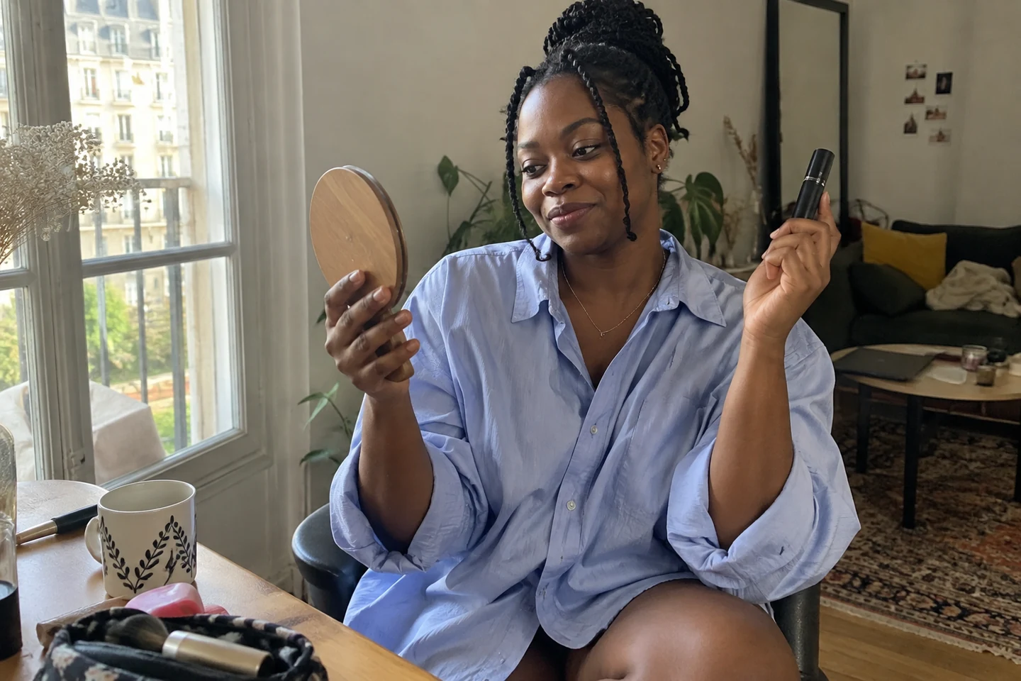 Une femme tient son mascara fermé devant un miroir