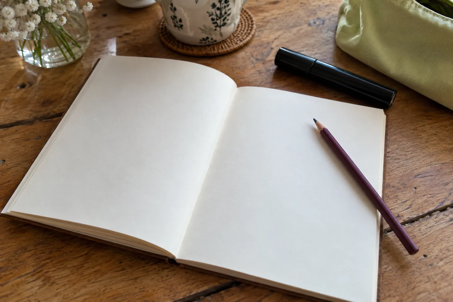Un carnet vierge, un crayon et un mascara fermé servent à préparer une observation.