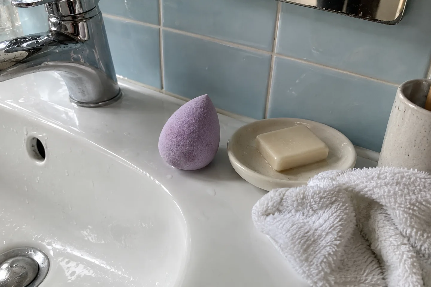 Éponge de maquillage, savon sans emballage et coupelle près d’un lavabo