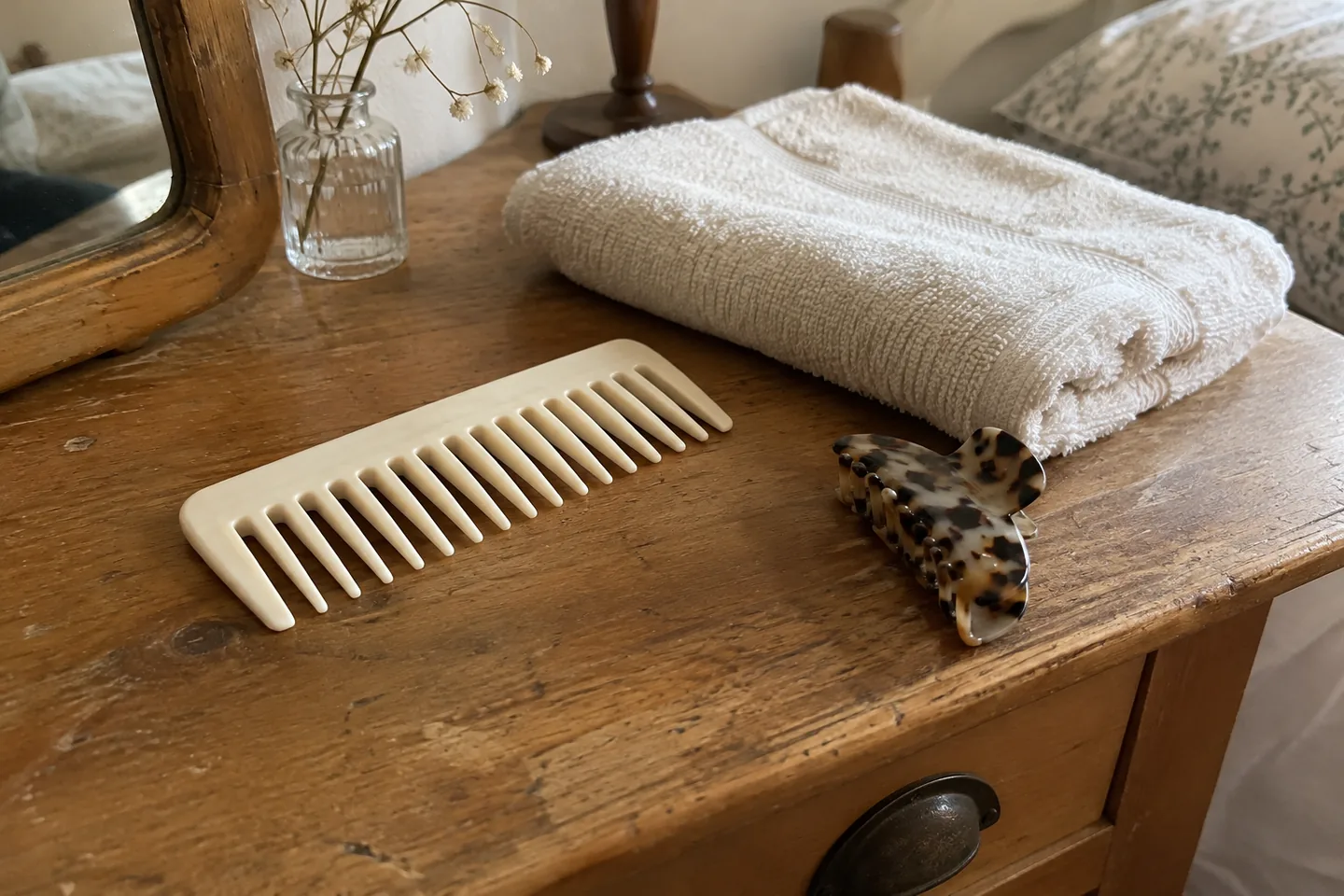 Peigne à dents larges et serviette de coton sur une table.